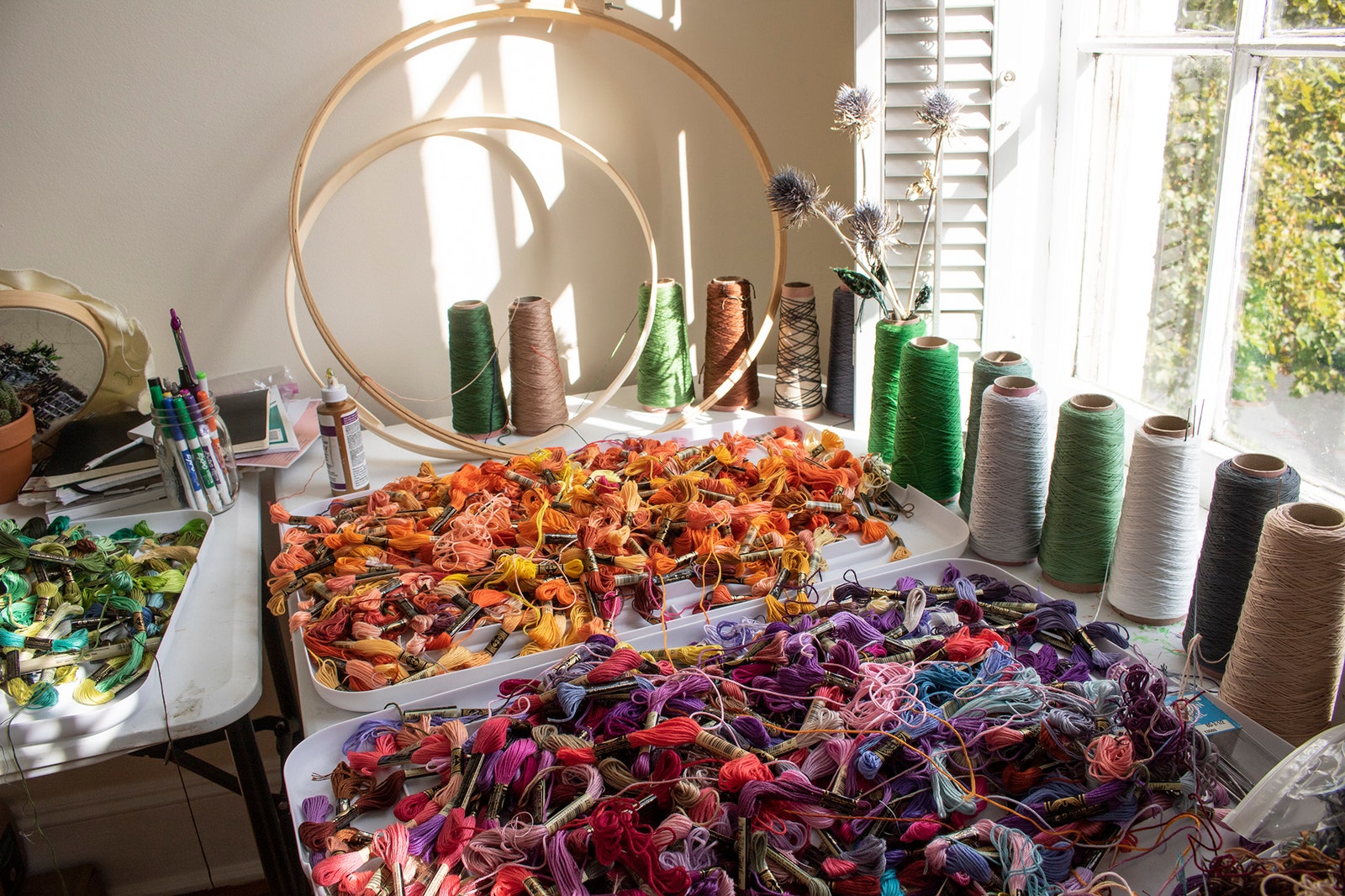 Basins filled with rainbows of thread and embroidery hoops inside Narrett's studio.