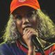 Jhené Aiko performing on stage wearing an orange cap